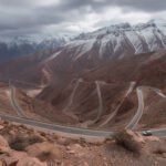 Col du Tizi n’Tichka Maroc – route de montagne sinueuse dans le Haut Atlas, sommets rocheux et enneigés, paysage spectaculaire avec voiture isolée, col entre Marrakech et Ouarzazate